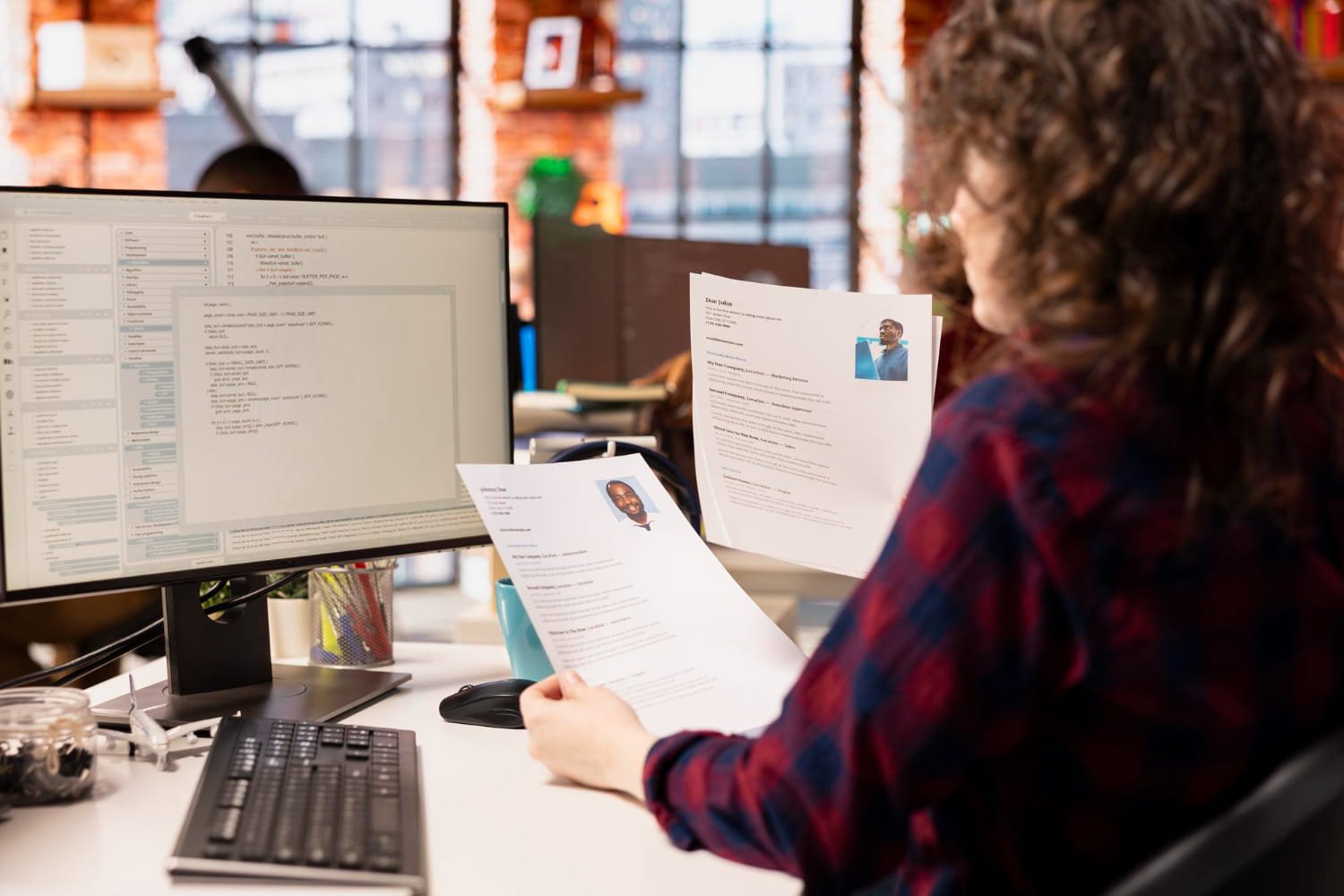 Professional resume document on a desk with laptop and coffee cup in background